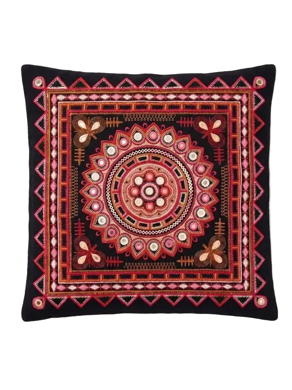 A square black throw pillow featuring an intricate, colorful embroidered mandala and geometric patterns in red, pink, orange, and white.