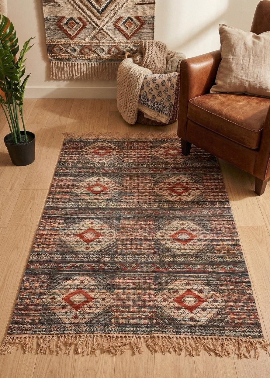 Patterned rug on a wooden floor with a brown chair and plant in the background