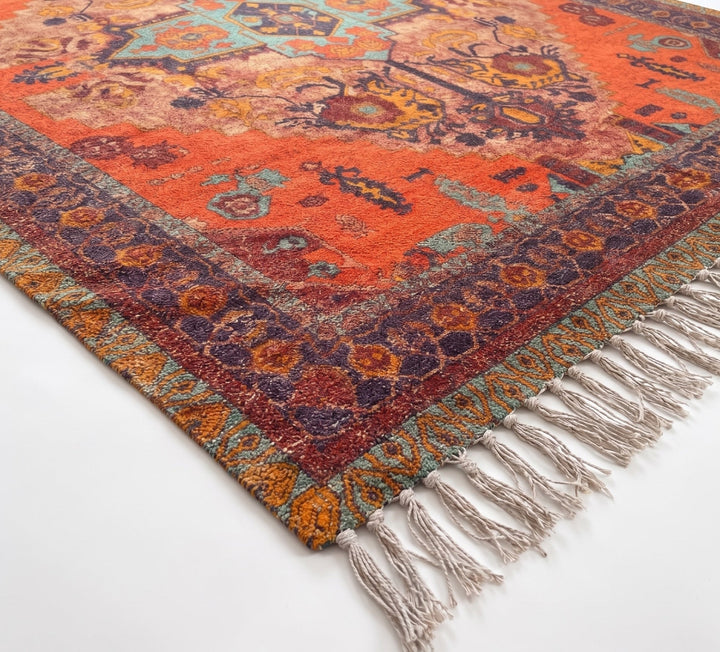 Close-up of a colourful patterned rug with tassels on a white background