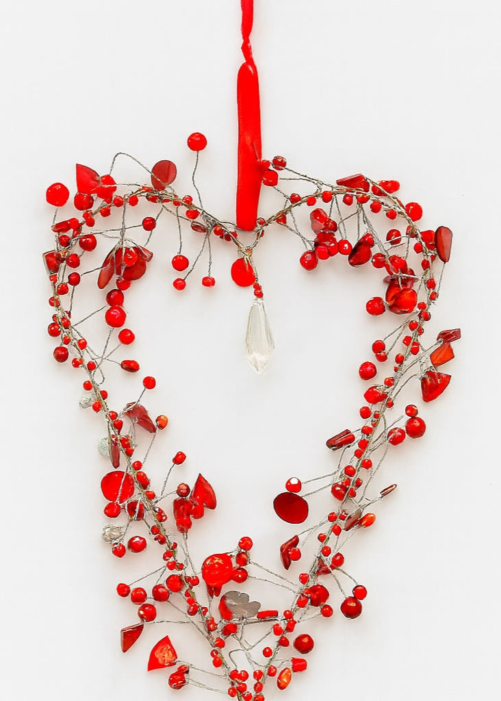 Heart-shaped decoration with red berries and a red string on a white background
