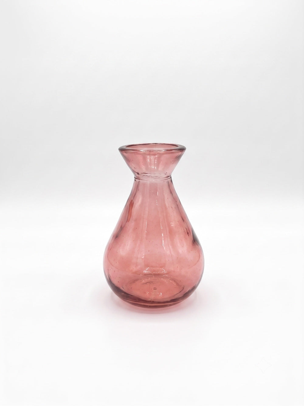 A small translucent pink glass vase with a flared rim and rounded body, photographed on a white studio background.