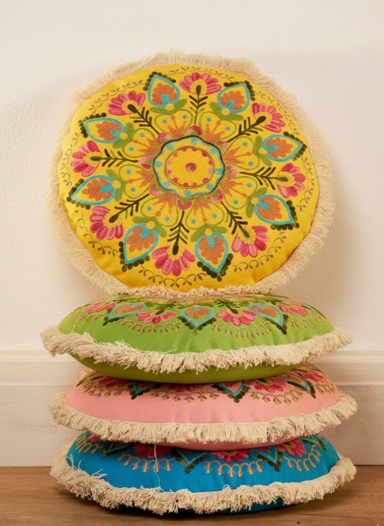 Stack of colourful round cushions with floral patterns on a wooden floor.
