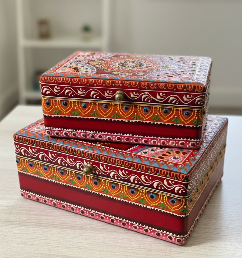 Two decorative boxes with intricate patterns stacked on a light surface.