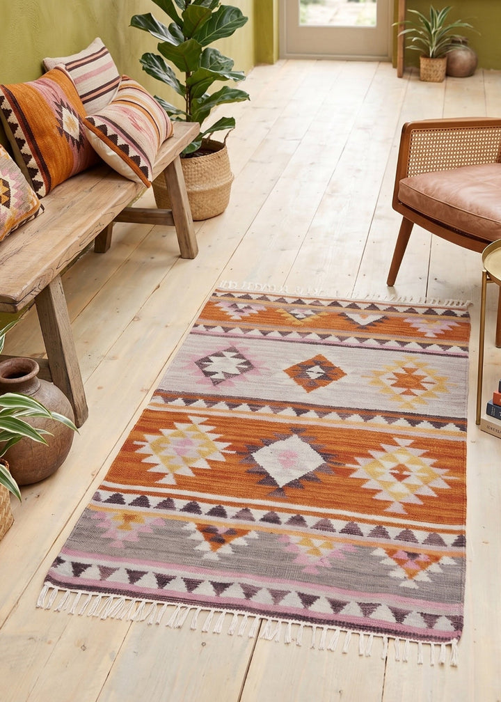 Living room with a patterned rug, wooden furniture, and plants.
