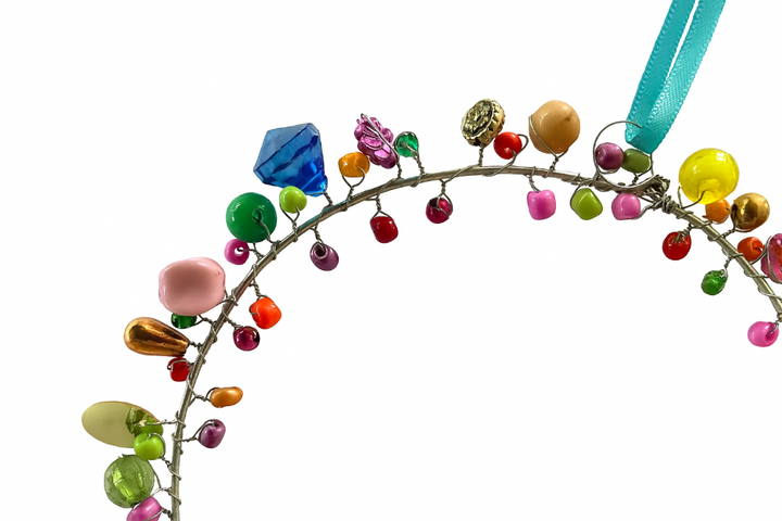 Small Decorative wreath with colourful beads and a blue ribbon on a white background