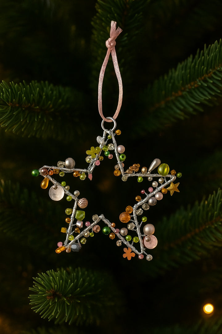 Decorative star ornament with beads hanging on a Christmas tree.