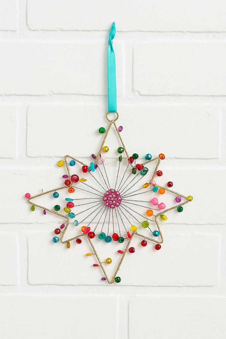 Decorative star-shaped ornament with colorful beads and a pink centre on a white background