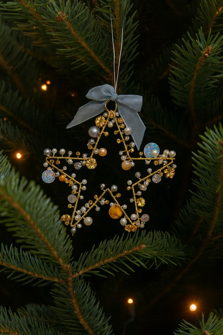Decorative star ornament with beads hanging on a Christmas tree.