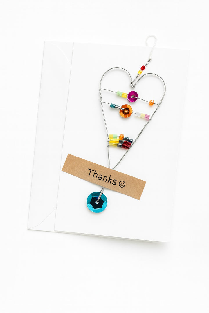 Heart-shaped toy with colorful beads and a 'Thanks' card on a white background