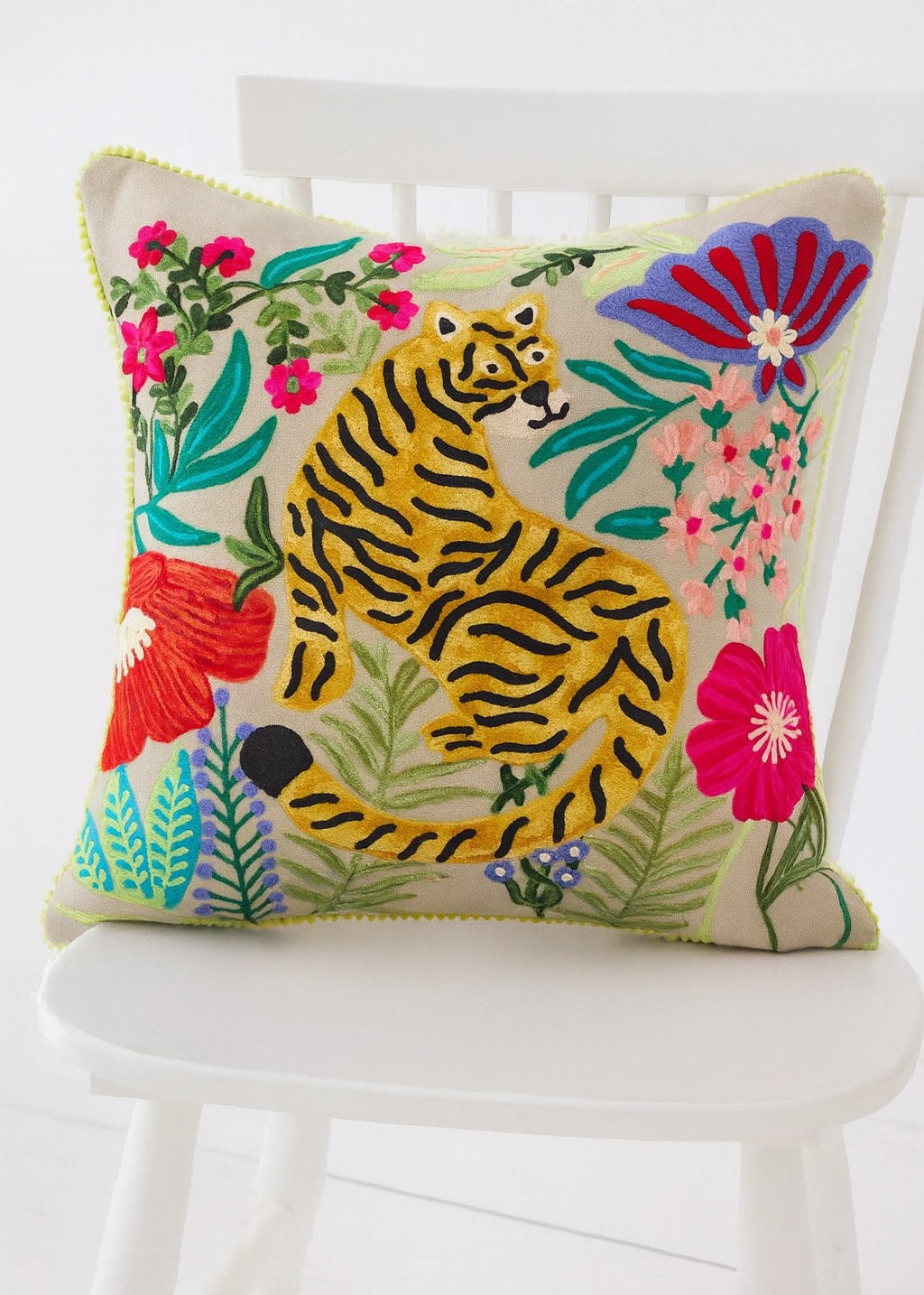Decorative pillow with a tiger and floral design on a white chair