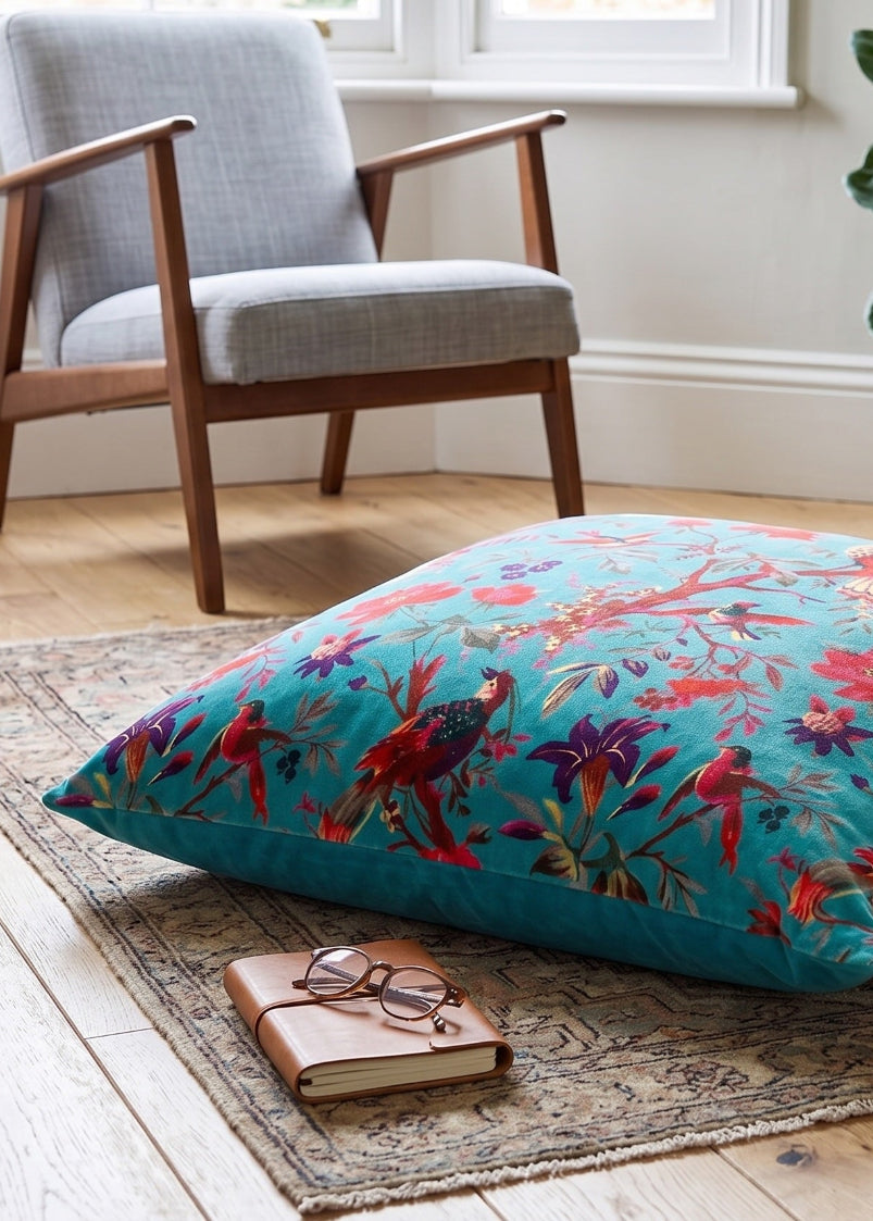 Colourful floral pillow on a rug in a room with a chair and plant