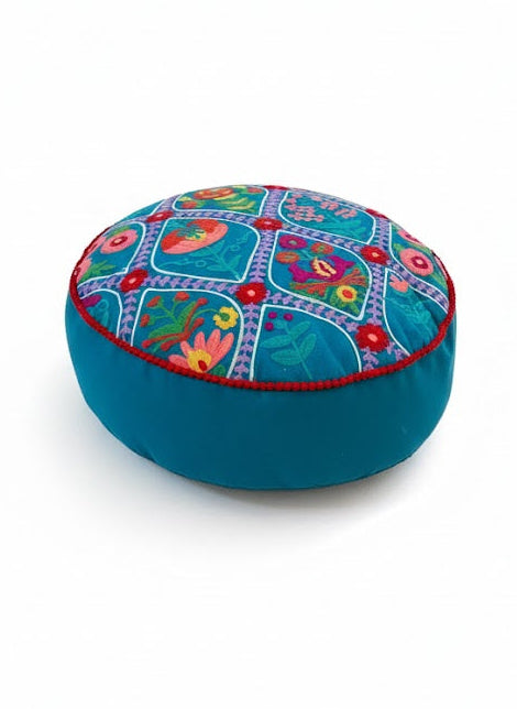 Round blue cushion with colourful floral patterns on a white background