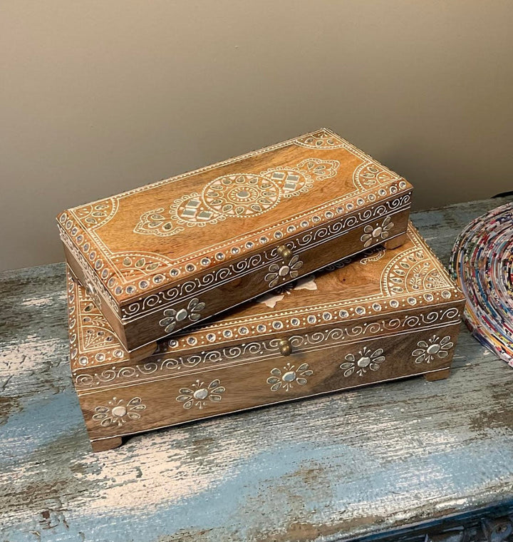 Two wooden boxes with intricate handmade design on a blue indian cabinet.