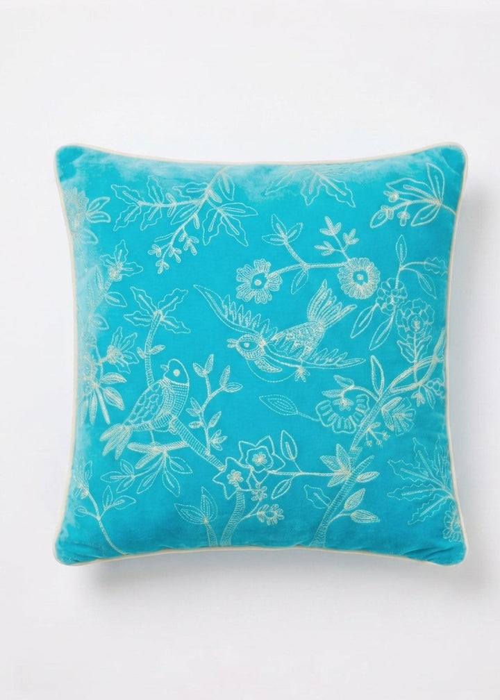 Turquoise pillow with floral and bird pattern on a white background