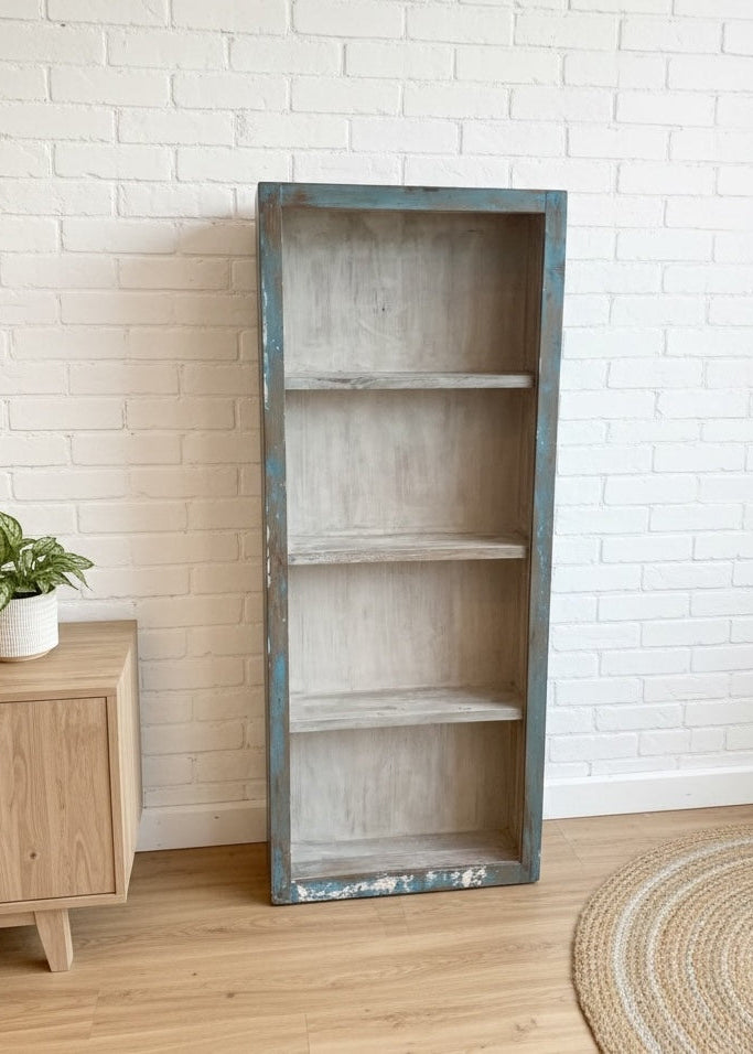 Tall Wooden Glass bookshelf display cabinet with distressed finish in a room with wooden floor and white brick wall.