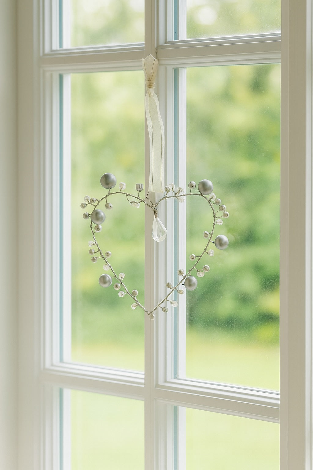 Heart-shaped decorative wreath with pearls hanging on a window