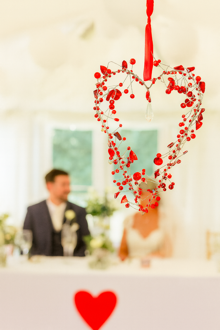 Decorative heart-shaped arrangement with red berry bead on a blurred wedding background