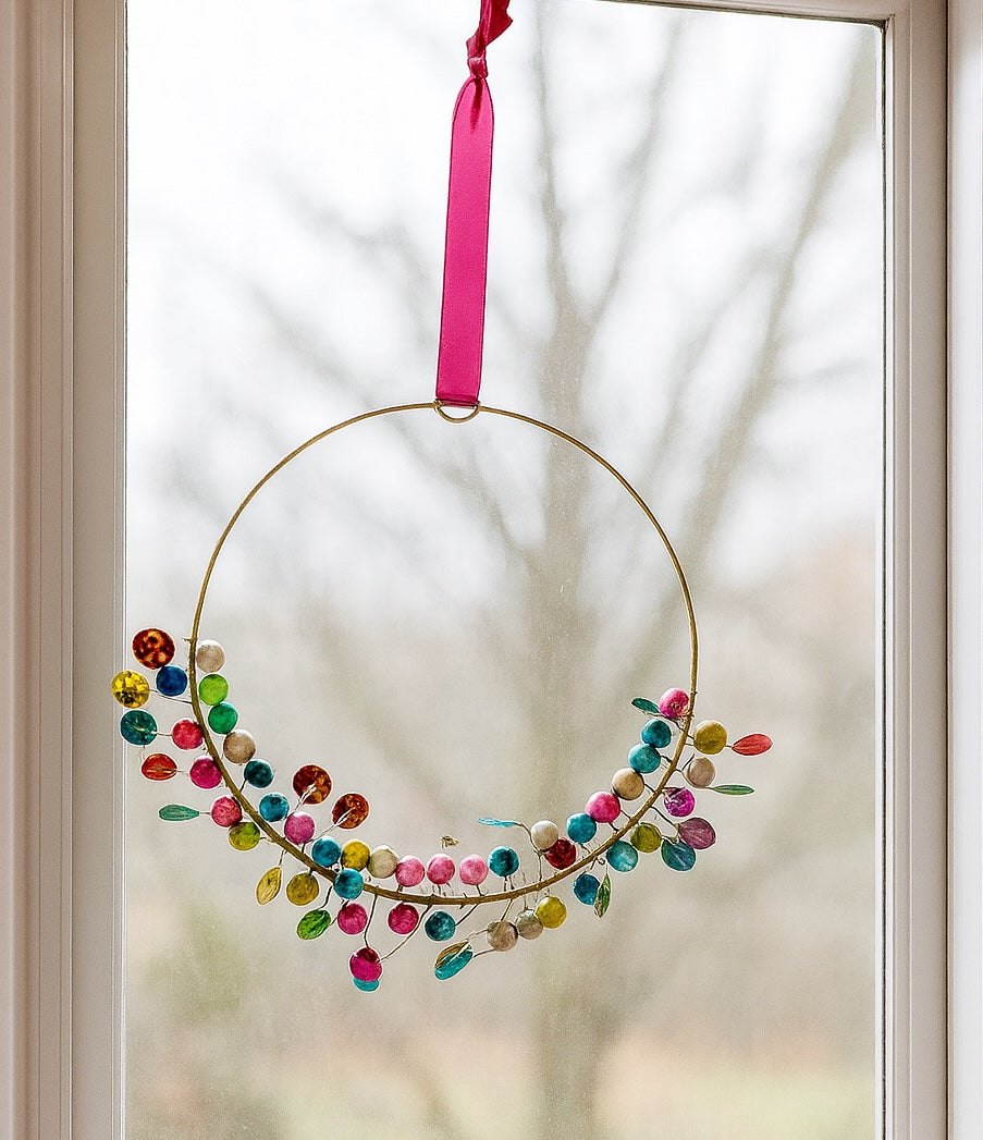 Decorative Hanging with colourful beads and a pink ribbon hanging on a glass door.