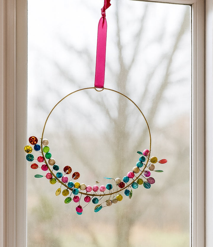 Decorative Hanging with colourful beads and a pink ribbon hanging on a glass door.