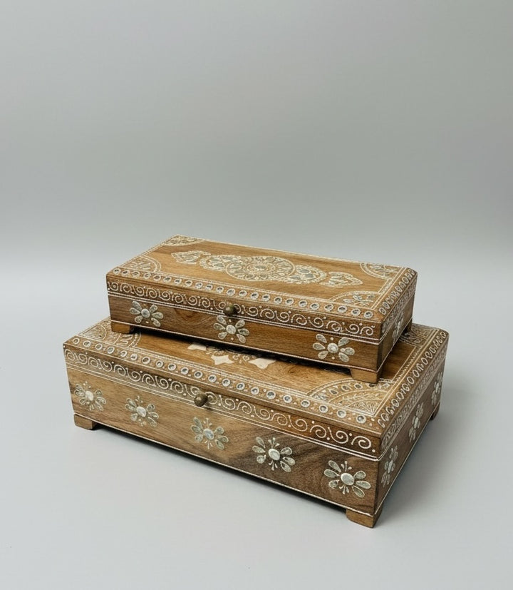 Two wooden boxes with floral and tribal patterns on a light grey background