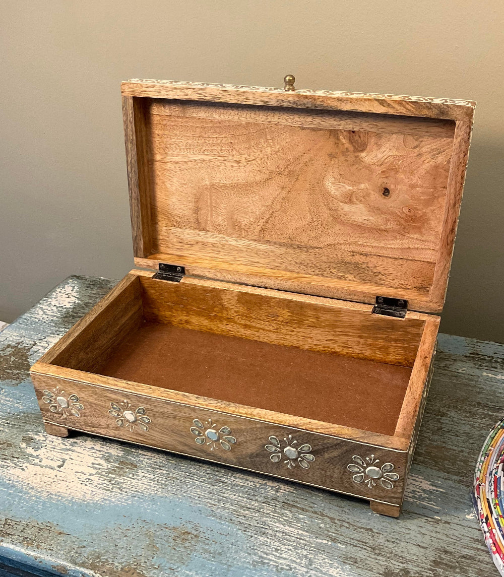 Wooden jewellery box with floral and tribal designs on a wooden surface