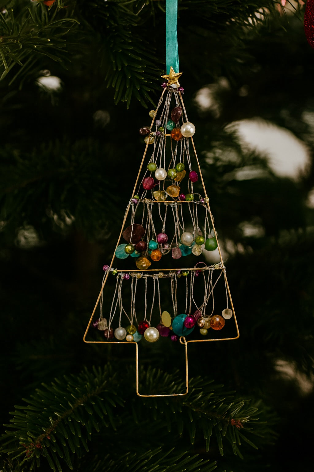 Decorative Christmas tree ornament with colourful beads hanging on a tree.