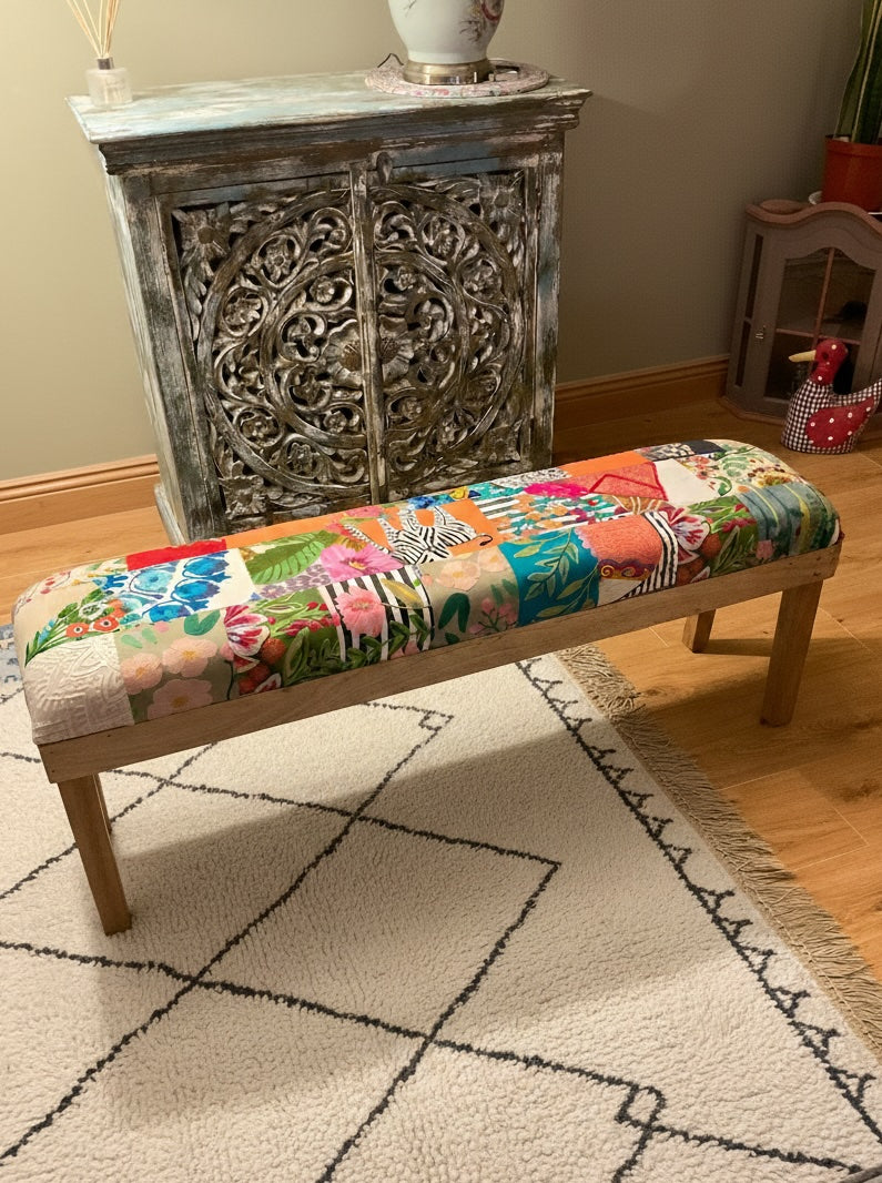Colourful patchwork bench in a room with a decorative cabinet.