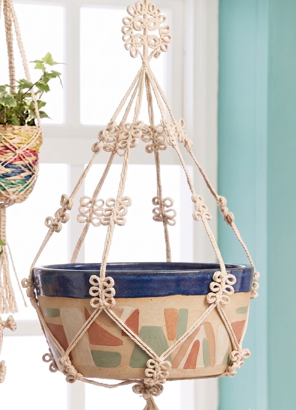 Hanging planter with decorative macrame holder against a light background