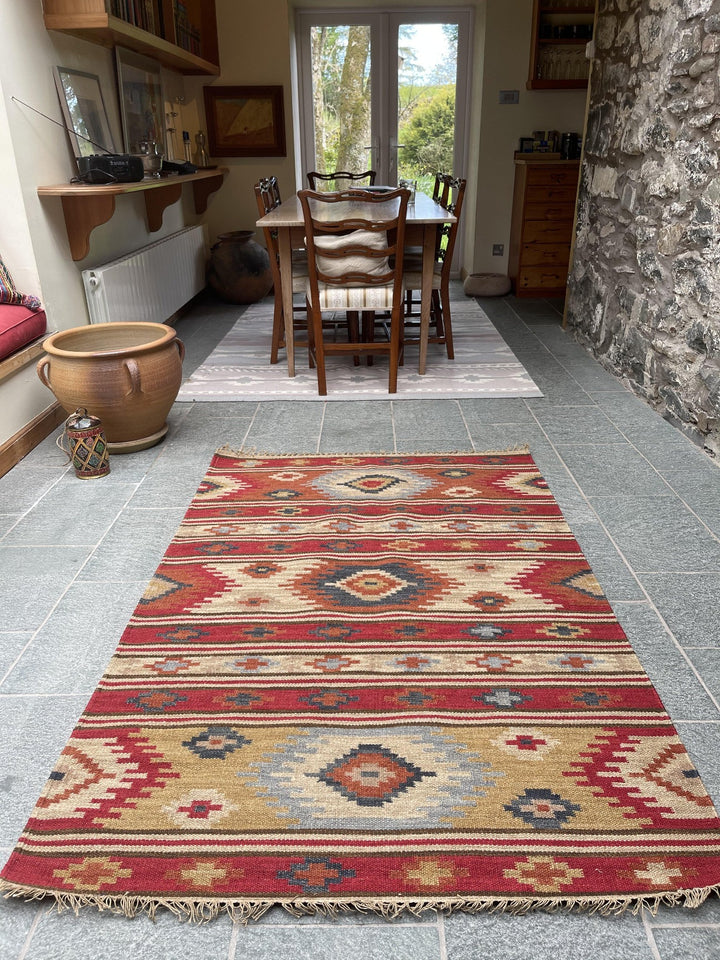 Kilim wool area rug on stone floor in a dining area with wooden table and chairs