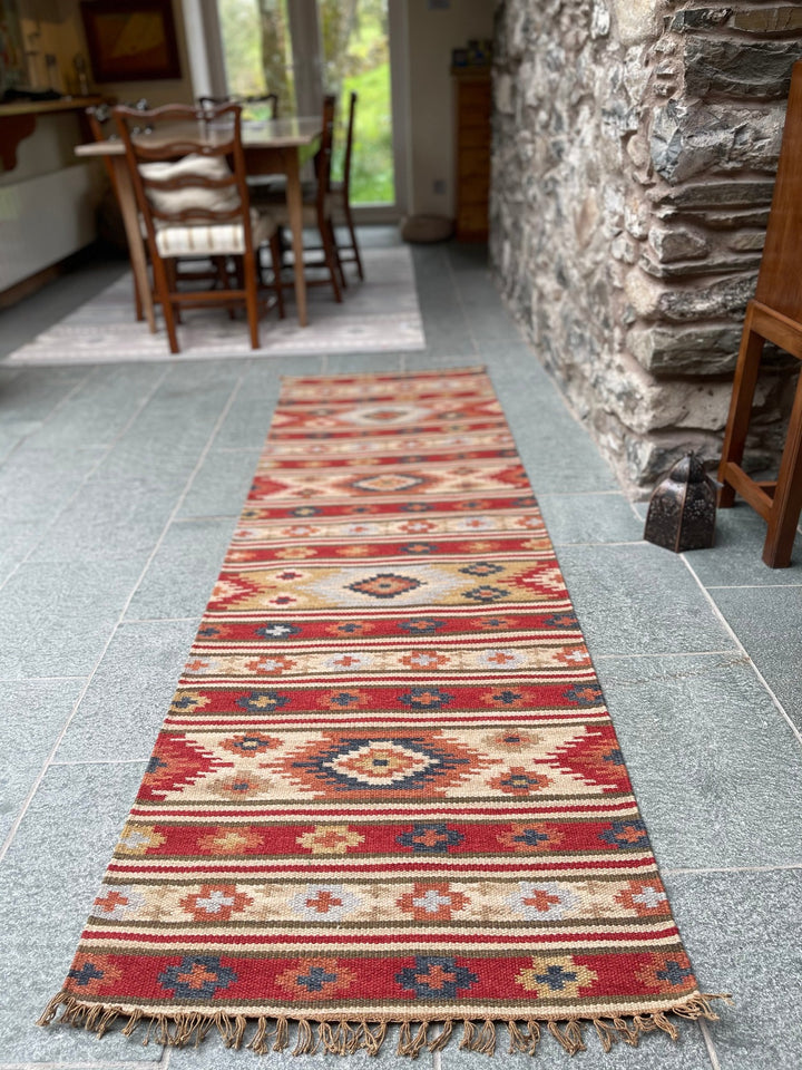 Kilim wool rug runner on tiled floor in a dining area with wooden table and chairs
