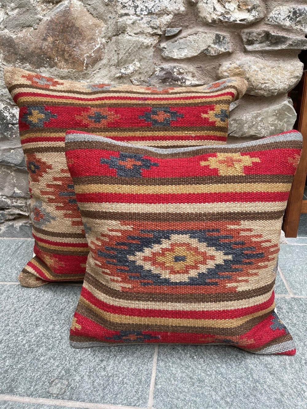 A pair of red geometric kilim cushion covers on a stone floor 