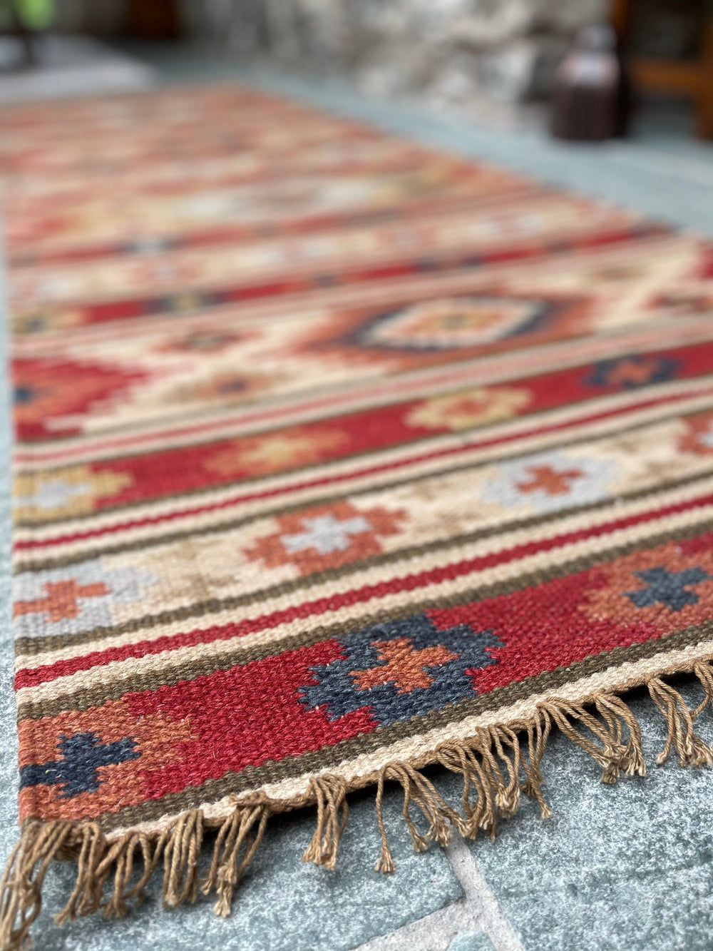 Close-up of kilim wool rug weave, showing red, cream and blue geometric diamond pattern