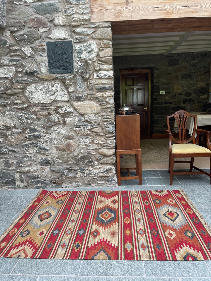 Kilim wool rug laid on stone floor against a rustic stone wall interior